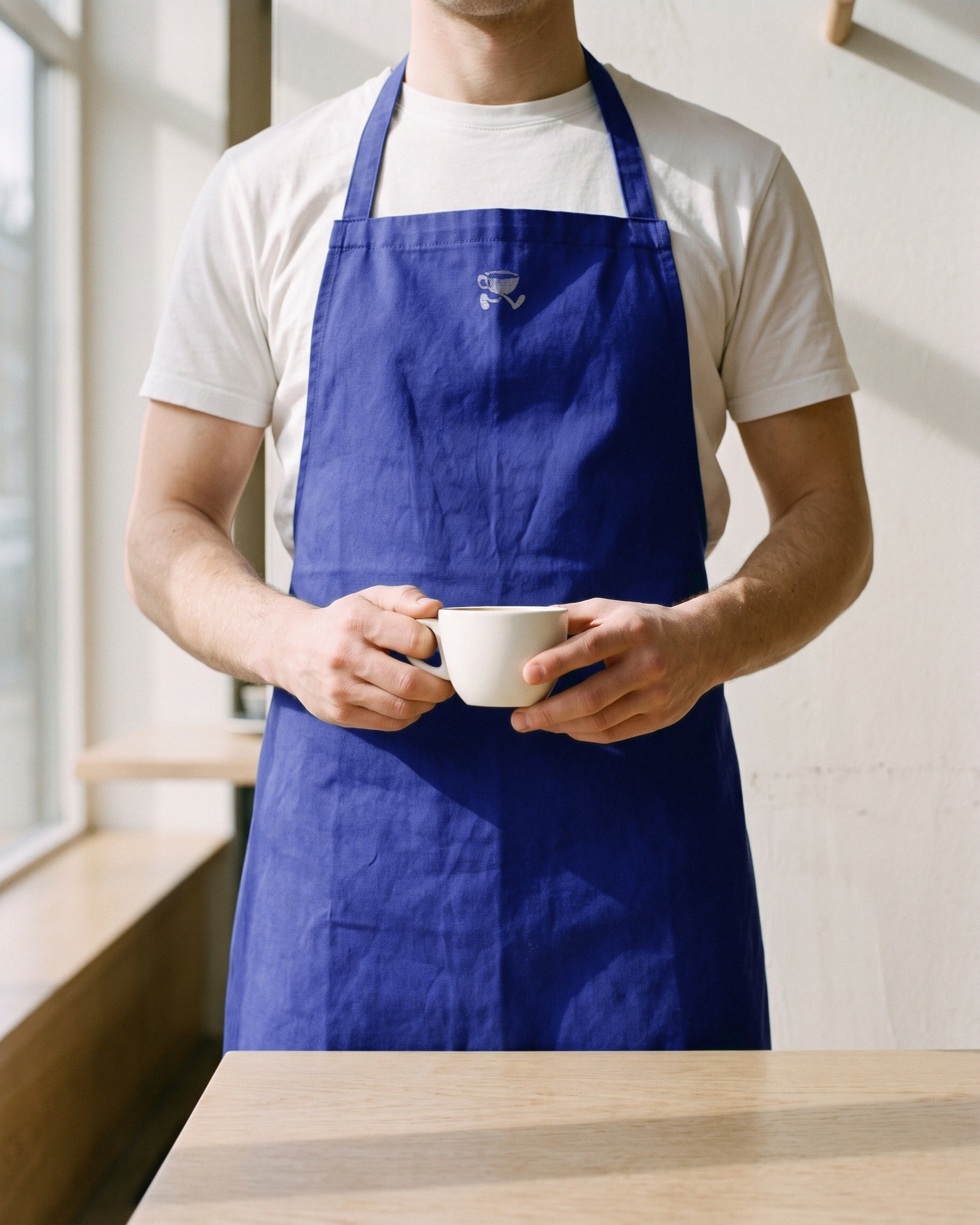 A barista in a blue apron with the cup printed small.