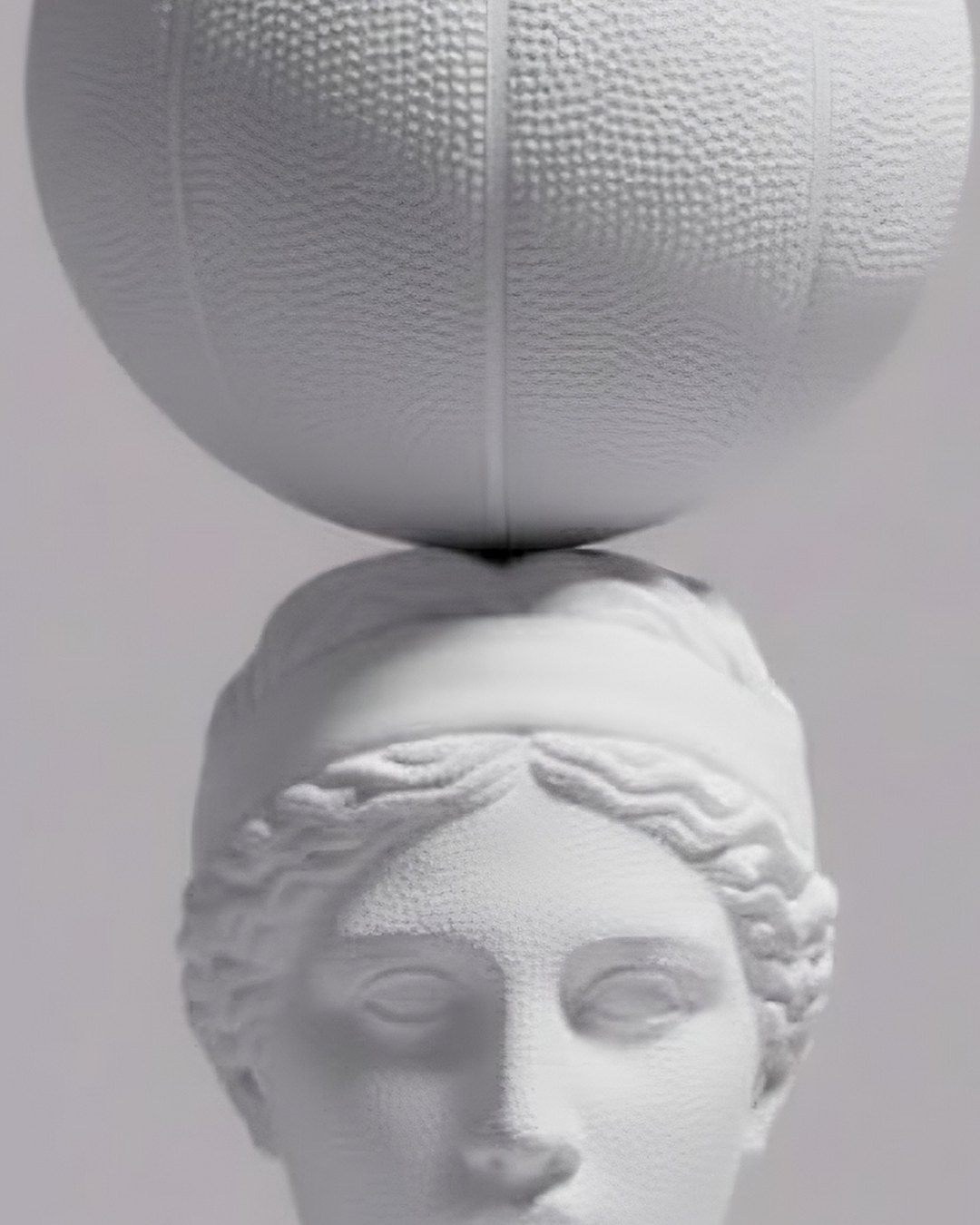 Two white basketballs balanced on a classical bust