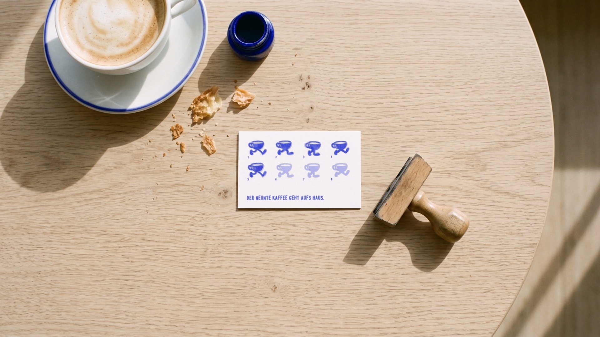 A loyalty card with eight walking cups, five of them stamped, next to the rubber stamp.
